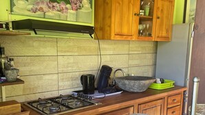A kitchen with wooden cabinets, a gas stove, a coffee maker, and a sink. - Comfort bungalow (Saint-Paul)