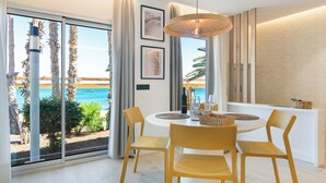 A modern dining area with a round table, yellow chairs, and a hanging light fixture.
