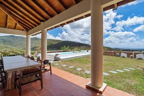 Une terrasse extérieure avec une piscine, des meubles en bois et une vue sur les montagnes.