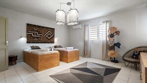 A modern bedroom with two wooden beds, a geometric rug, and a wall-mounted light fixture.