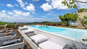A swimming pool with lounge chairs and sun loungers, surrounded by a landscaped area with a view of the landscape.