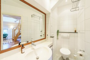 Un baño moderno con un espejo grande, lavamanos blanco y retrete.