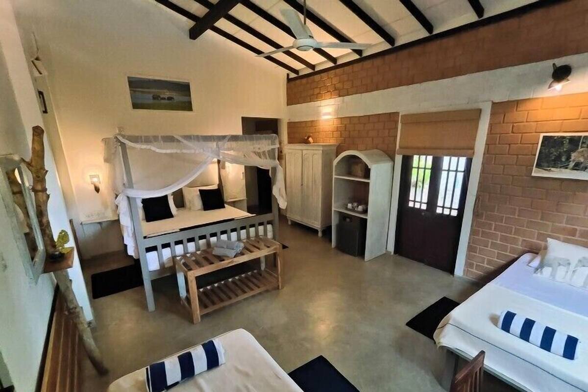 Una habitación con cama, banco, armario y una mesita.