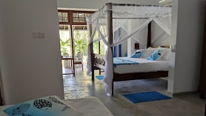 Una habitación con una cama bajo un dosel, una mesita con mantel azul y vistas al exterior.