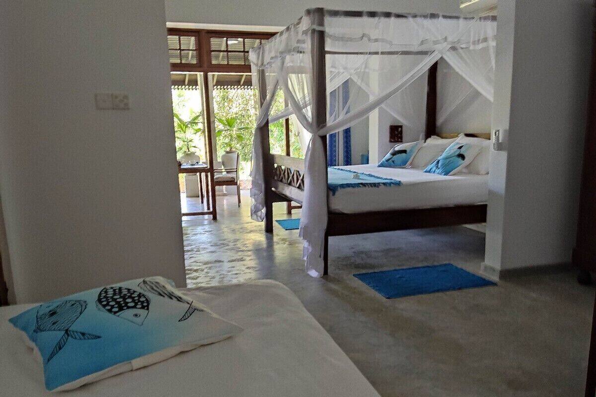 Una habitación con una cama bajo un dosel, una mesita con mantel azul y vistas al exterior.
