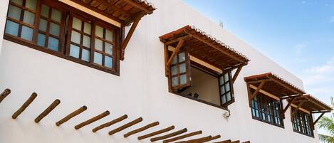 A building with multiple windows, some with wooden shutters, and a series of wooden beams on the facade.