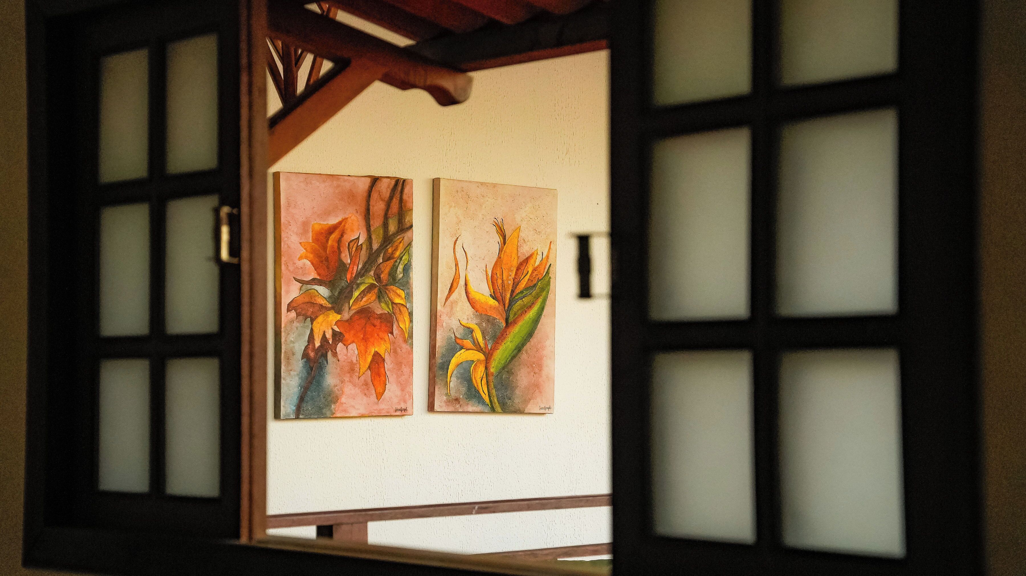 A room with a traditional Japanese shoji screen door, a wooden beam ceiling, and two framed paintings on the wall.