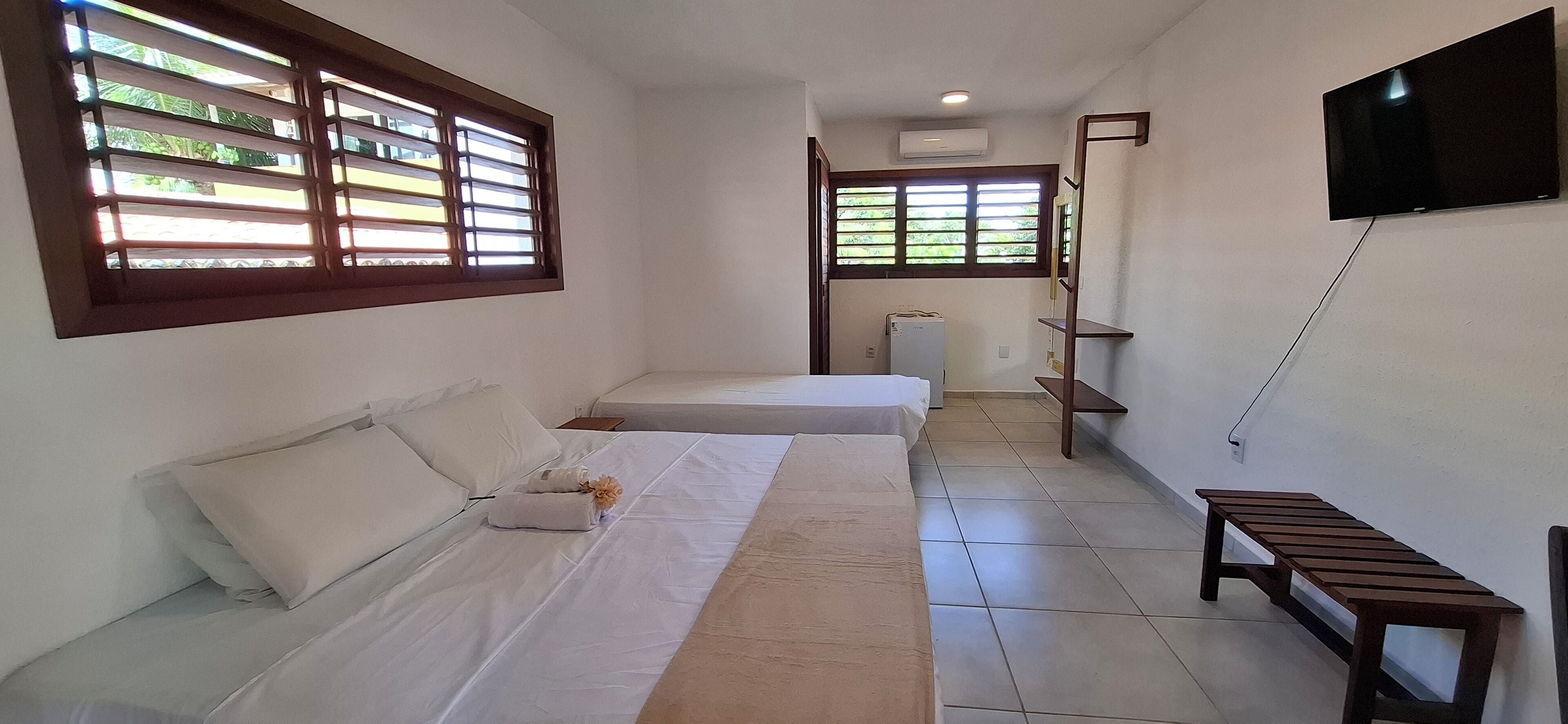 Une chambre d’hôtel avec deux lits, un téléviseur fixé au mur et une petite table.