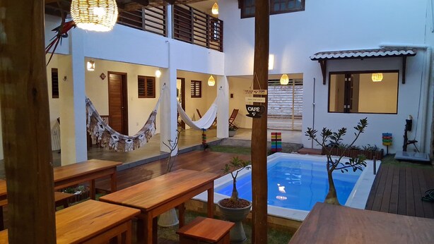 Area piscina con panchine di legno, un'amaca e un cartello che indica un caffè.
