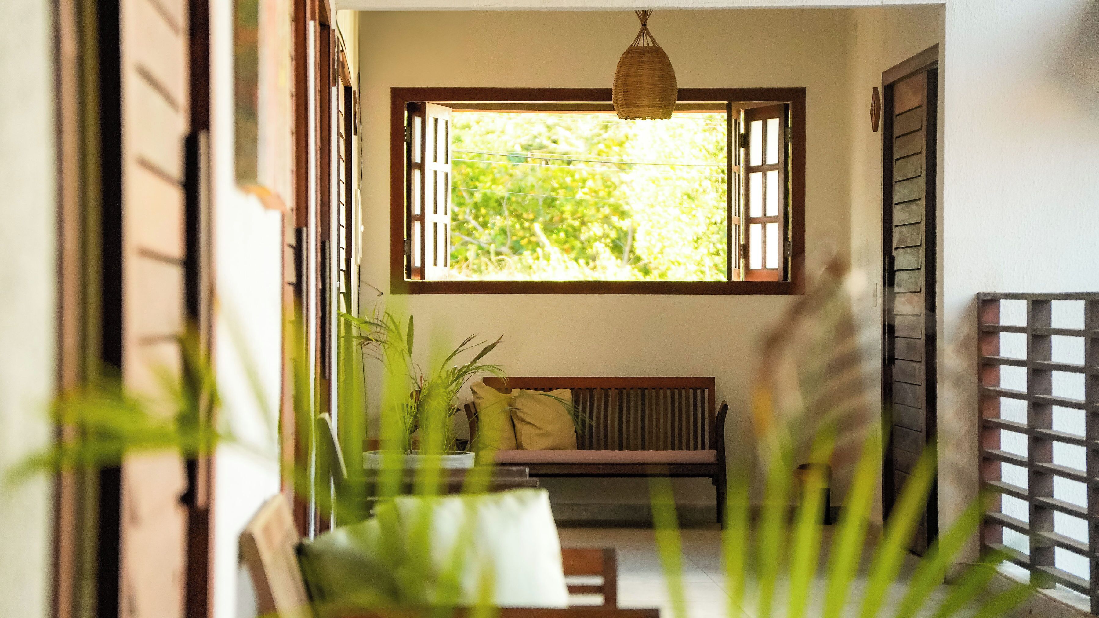 A room with a wooden bench, a hanging light fixture, and a window with open shutters.