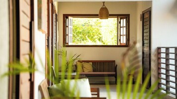 A room with a wooden bench, a hanging light fixture, and a window with open shutters.
