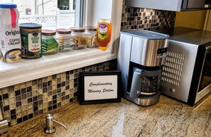 A kitchen with a coffee maker, a framed sign, and various food items on the counter.