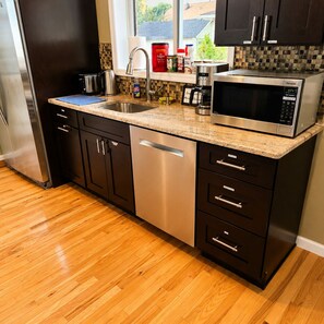 A modern kitchen with stainless steel appliances, a dishwasher, and a microwave.