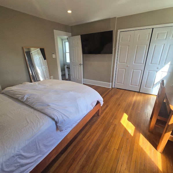 Un dormitorio con una cama de madera, un espejo grande y un armario.