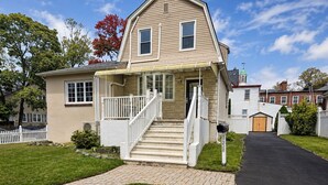 A two-story house with a front porch, a driveway, and a mailbox.