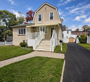 A two-story house with a front porch, a driveway, and a mailbox.
