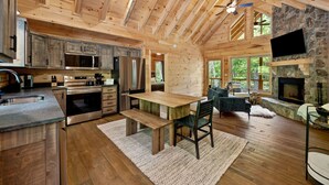 Un intérieur de chalet en bois spacieux, comprenant une cuisine, un coin repas et une cheminée en pierre.