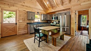 L’intérieur d’un chalet en bois comprend une cuisine, un coin repas et une grande porte en bois.