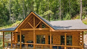 Une cabane en bois dotée d’un balcon, de grandes fenêtres et d’une cheminée.