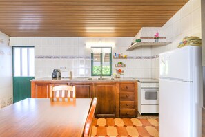 Uma cozinha com armários de madeira, geladeira branca, fogão e mesa de jantar com cadeiras.