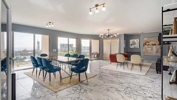 A spacious living area with a large dining table, blue chairs, a red sofa, and a fireplace. - Expo river View (Lisboa)