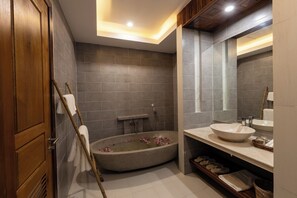Ein modernes Badezimmer mit freistehender Badewanne, einem Holzkosmetikschrank und einem großen Spiegel.