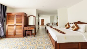 Habitación de hotel con un armario grande, un escritorio, una cama con muchas almohadas y un suelo estampado.