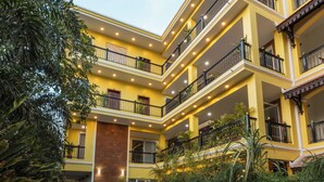 Un hotel con zona de piscina, varios balcones y abundante vegetación.