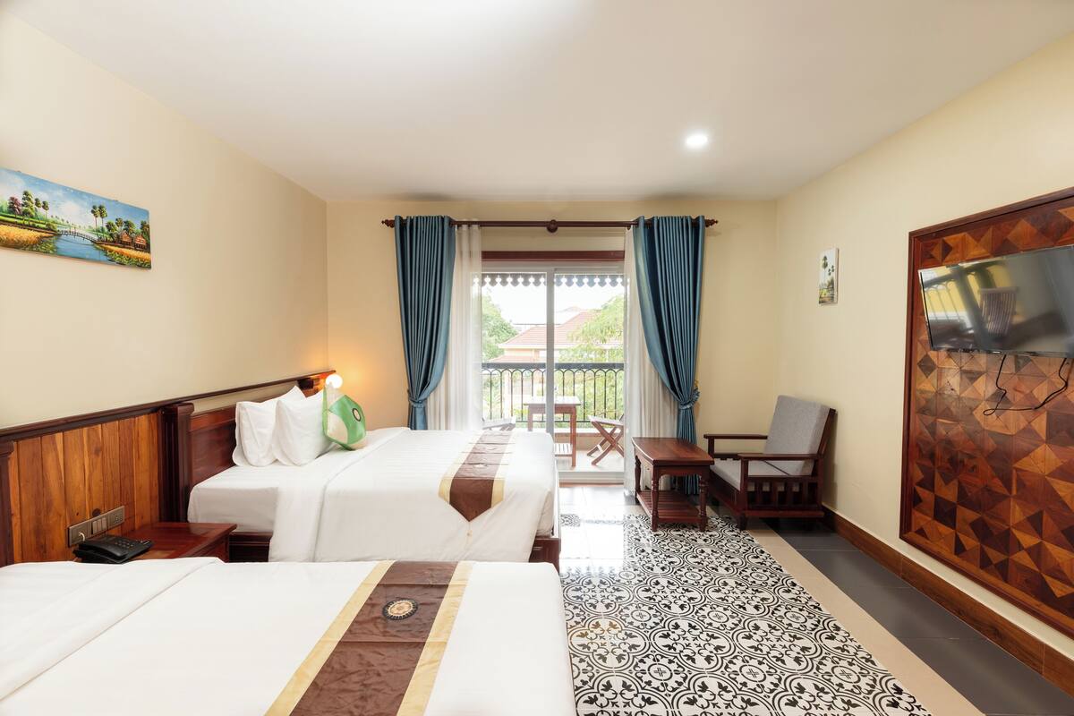 Une chambre d’hôtel avec deux lits, un balcon, une télévision et un sol à motifs.
