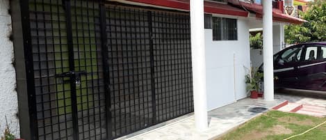 A gated entrance with a metal gate, a potted plant, and a parked car.