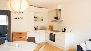 A modern kitchen with white cabinetry, a round dining table, and a built-in oven. - Stylish Central 4-person CPH Apt. (København)