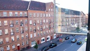 A street view with a row of red brick buildings, a bicycle parked on the sidewalk, and cars on the road. - Stylish Central 4-person CPH Apt. (København)
