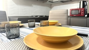 Una cocina moderna con una mesa de comedor dispuesta con platos y vasos amarillos, un microondas y una cocina a gas.