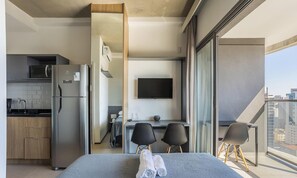 A modern hotel room with a balcony, a kitchen area, and a TV. - Studio in Condominium With Pool in Paraiso Onp1716 (São Paulo)