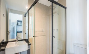 A modern bathroom with a glass shower enclosure, a white sink, and a visible toilet. - Studio in Condominium With Pool in Paraiso Onp1716 (São Paulo)