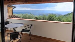 Ein Balkon mit Tisch und Stühlen, mit Blick auf eine Berglandschaft.