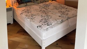 Quarto com uma cama, duas mesas de cabeceira, um criado-mudo e uma obra de arte na parede.