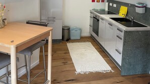 Cozinha moderna com frigorífico, fogão, pia e área de refeições com mesa e cadeiras.