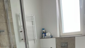 Casa de banho moderna com cabine de duche em vidro, sanita e lavatório.