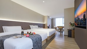 Habitación de hotel con dos camas, un escritorio y un ventanal grande.