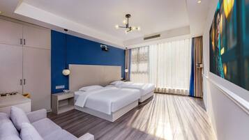Quarto de hotel moderno com uma cama grande, um sofá, uma escrivaninha e uma janela ampla com cortinas.
