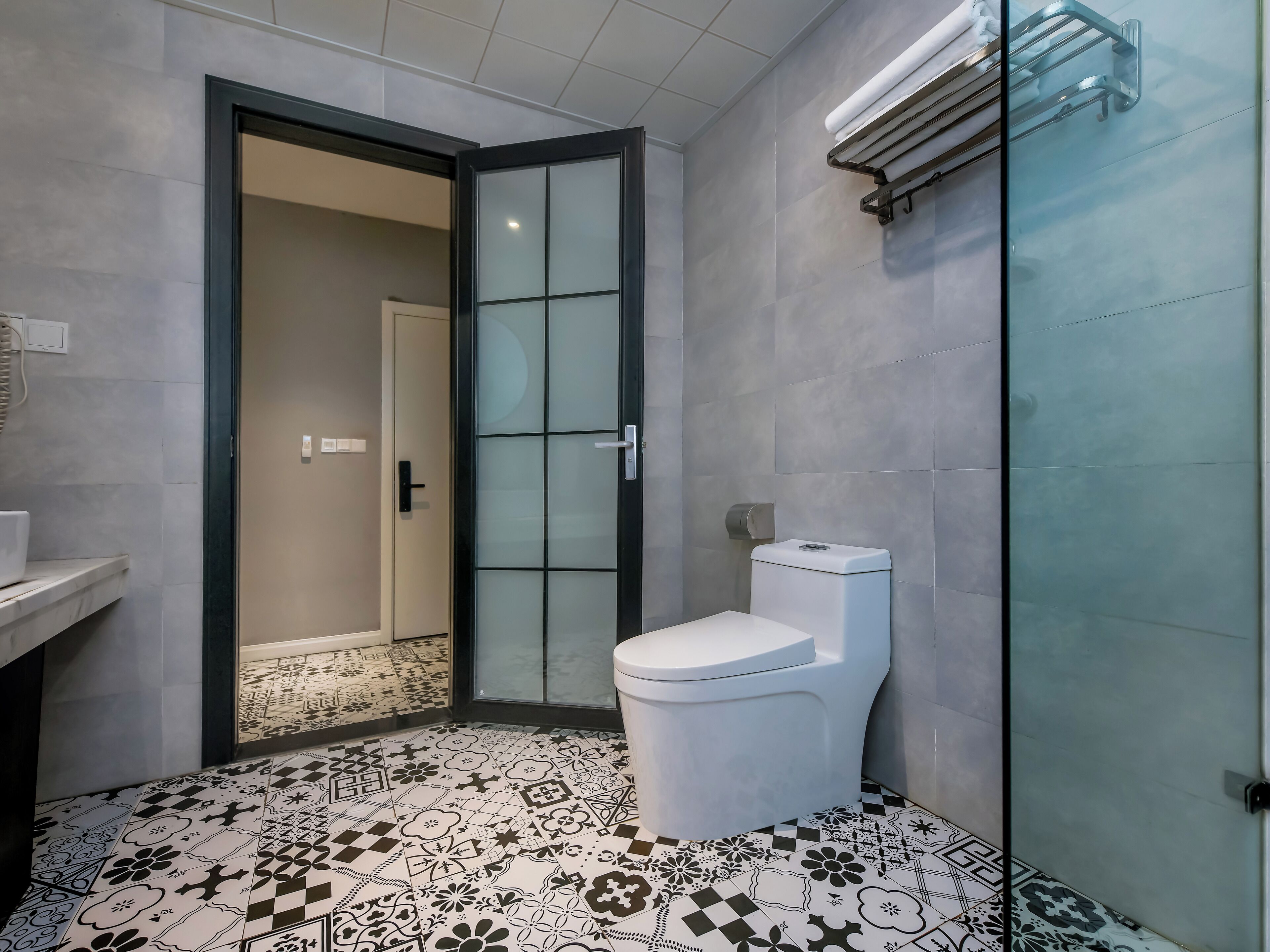 Une salle de bain comprenant des toilettes, un espace douche et un carrelage décoratif.
