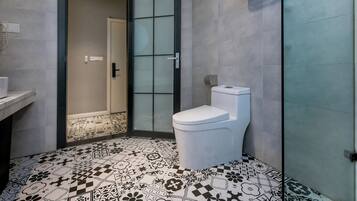 Une salle de bain comprenant des toilettes, un espace douche et un carrelage décoratif.