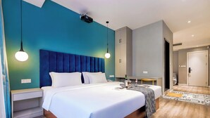 Una habitación de hotel moderna con una cama grande, mesitas de noche, un armario y un baño visible a través de una puerta abierta.