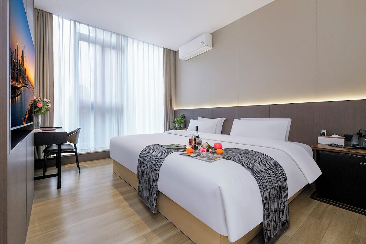 Una habitación de hotel moderna con una cama grande, un escritorio y un televisor.