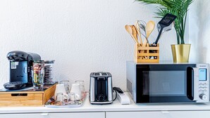 A kitchen counter with a coffee maker, toaster, microwave, and a plant.