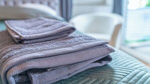 A neatly folded, textured blanket on a bed with a patterned bedspread.