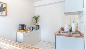 A compact kitchen with a microwave, coffee maker, and a small plant.