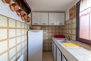 Une cuisine de taille réduite, équipée d’un réfrigérateur, d’un évier et de placards.