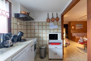 A compact kitchen with a microwave, coffee maker, and a trash bin.